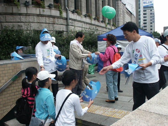 한국전력 중부지점 직원들이 청계천 시민 걷기대회에 참여한 시민들에게 선캡을 나눠주고 있다.